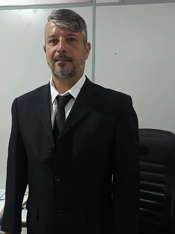 Louis Menezes em retrato profissional, vestindo terno preto